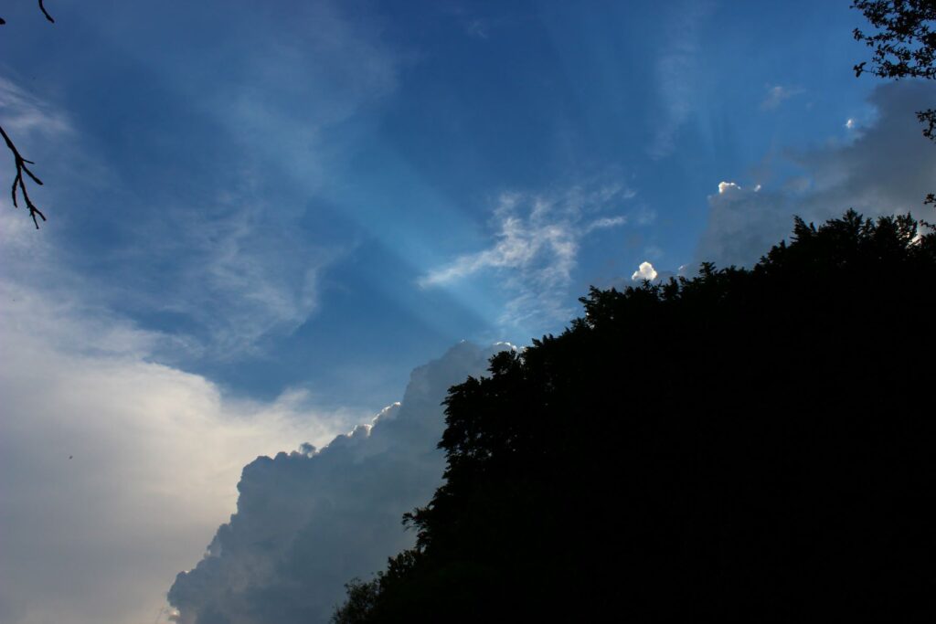 Wolkenstimmung, Sonnenstrahlen hinter einer Hügelsilhouette