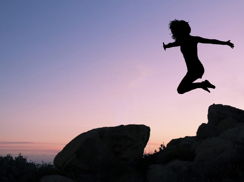 silhouette einer springenden Frau über Felsen